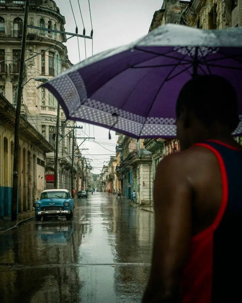 Fotografie Tipps - Jörg Nicht - Kuba -Person auf der Straße mit Regenschirm - Auto